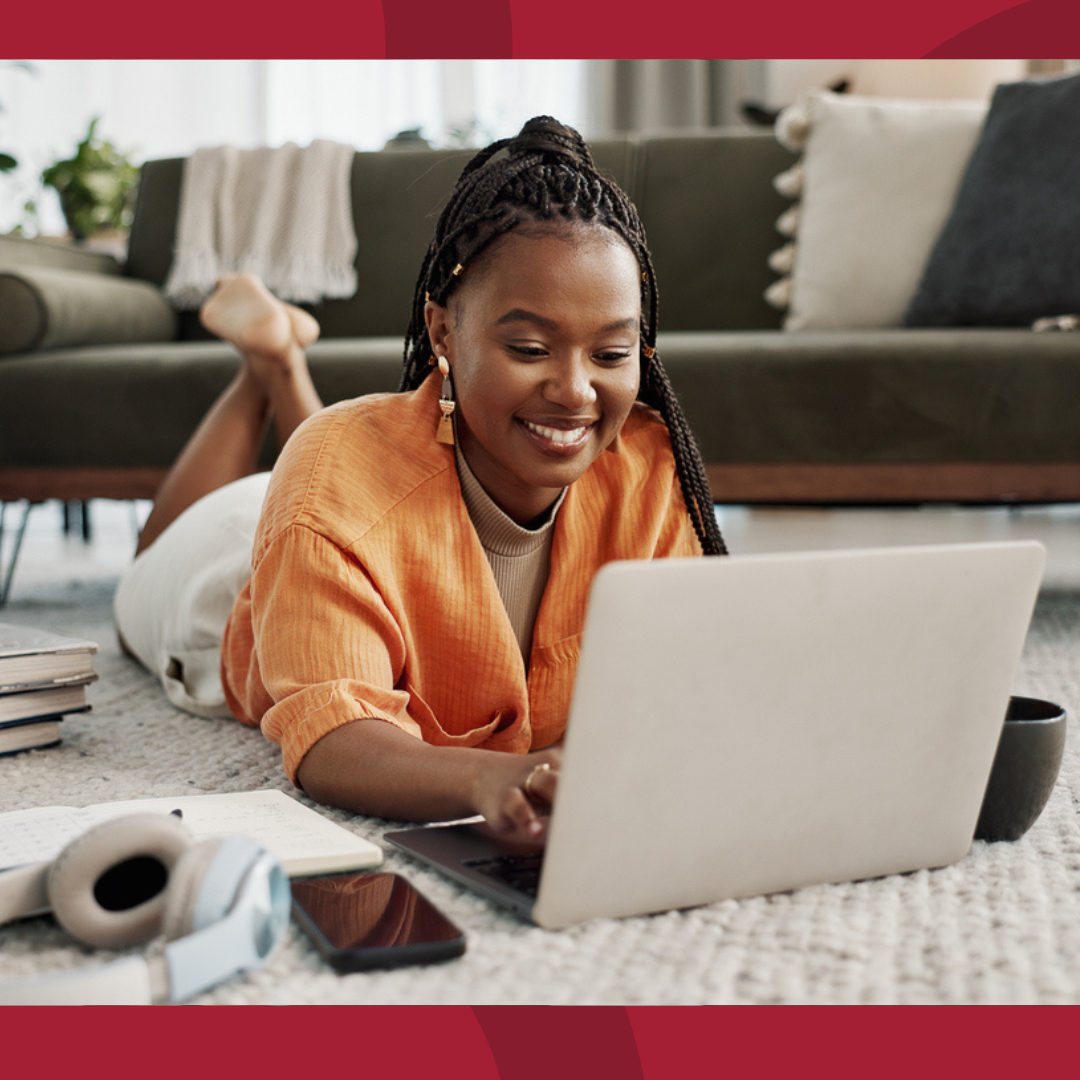 Woman laying on the floor, working on her laptop.